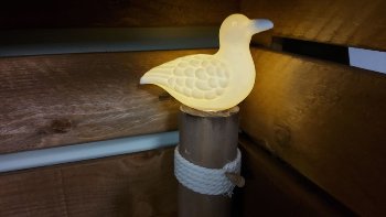 Weiße Keramik Möwe auf Holzpoller mit Licht